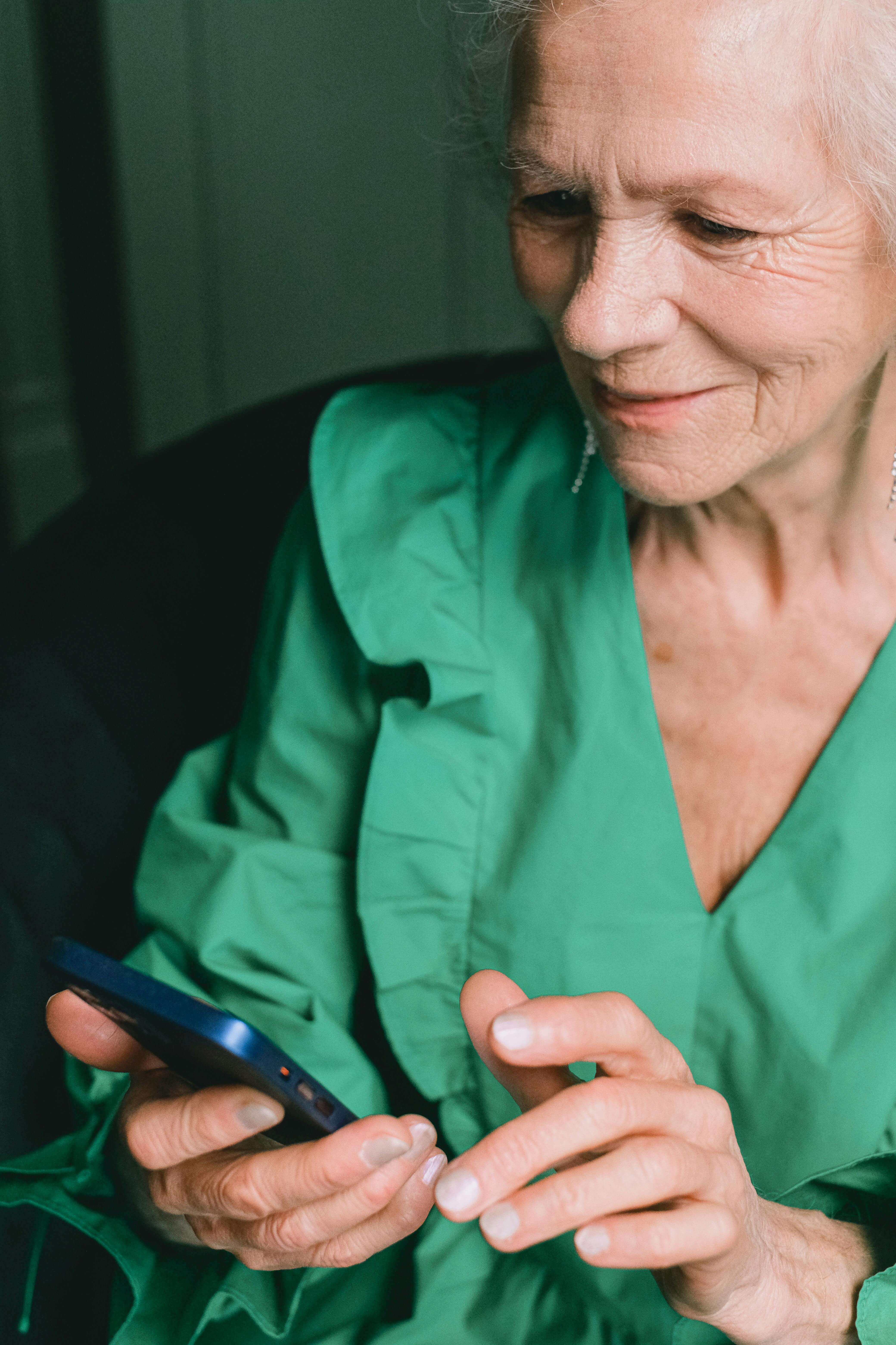 Ältere Frau tippt zufrieden auf ihrem Smartphone